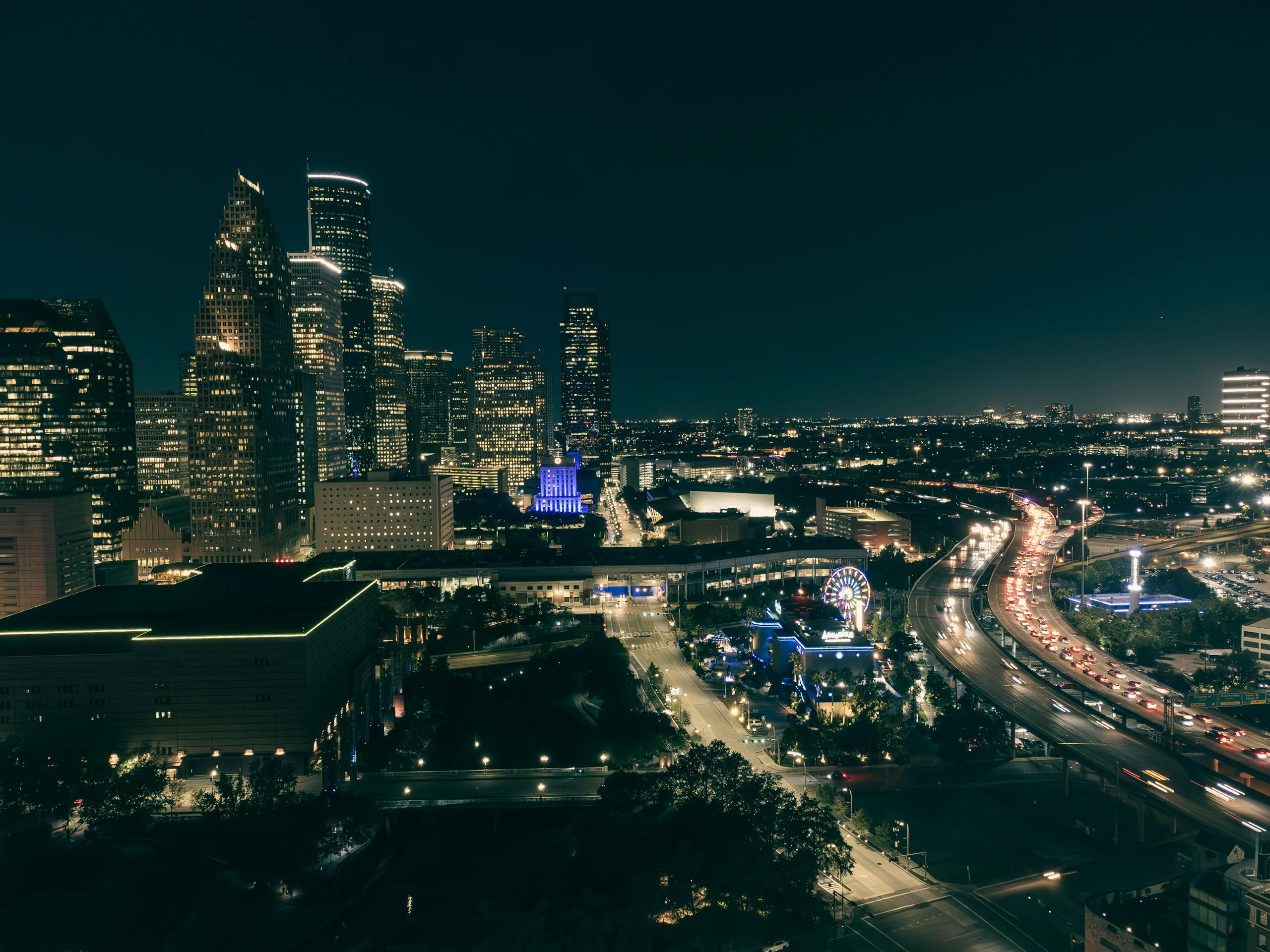 A breathtaking night view of downtown skyline with illuminated buildings and bustling traffic.